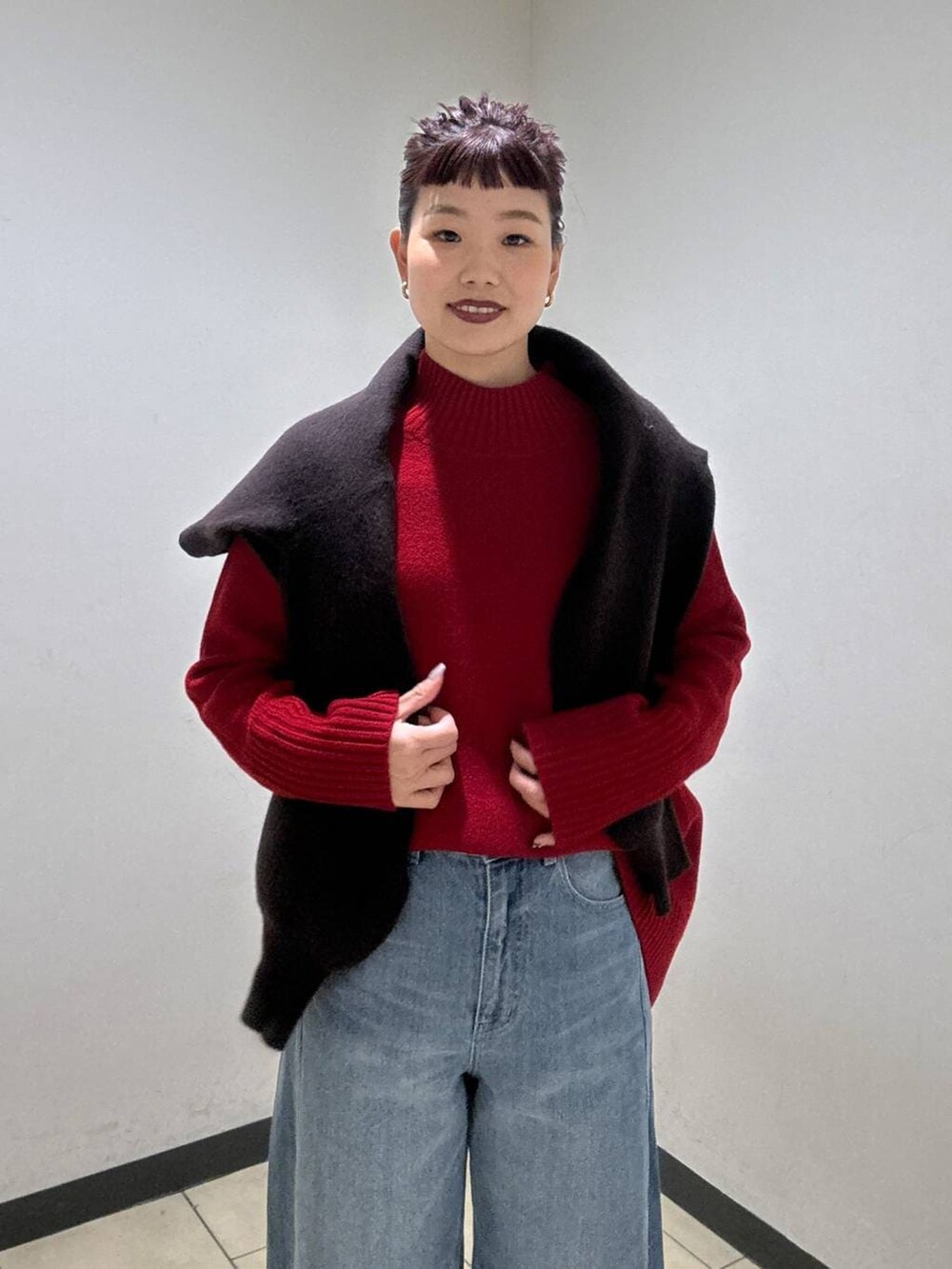 ブルー系のデニムパンツ、ブラック系のブーツ、レッド系のニット/セーターを着用したレディースの冬コーディネートの6枚目の写真