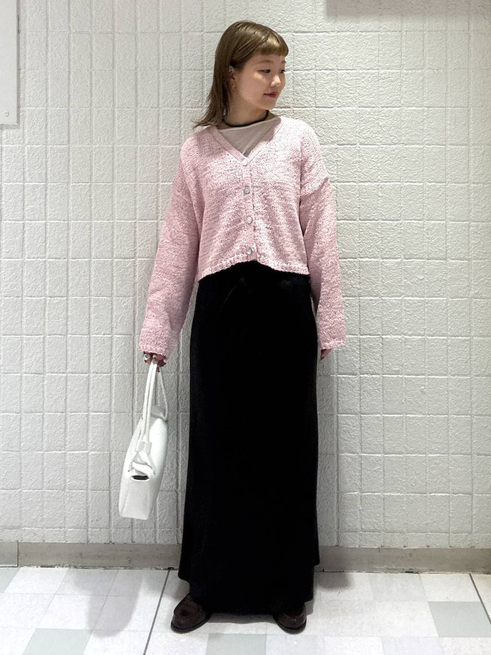 ホワイト系のショルダーバッグ、ピンク系のカーディガン/ボレロ、ブラック系のスカートを着用したレディースの春コーディネートの2枚目の写真