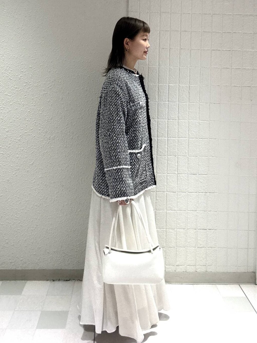 ホワイト系のスカート、ブラック系のノーカラージャケット、ホワイト系のショルダーバッグを着用したレディースの春コーディネートの3枚目の写真