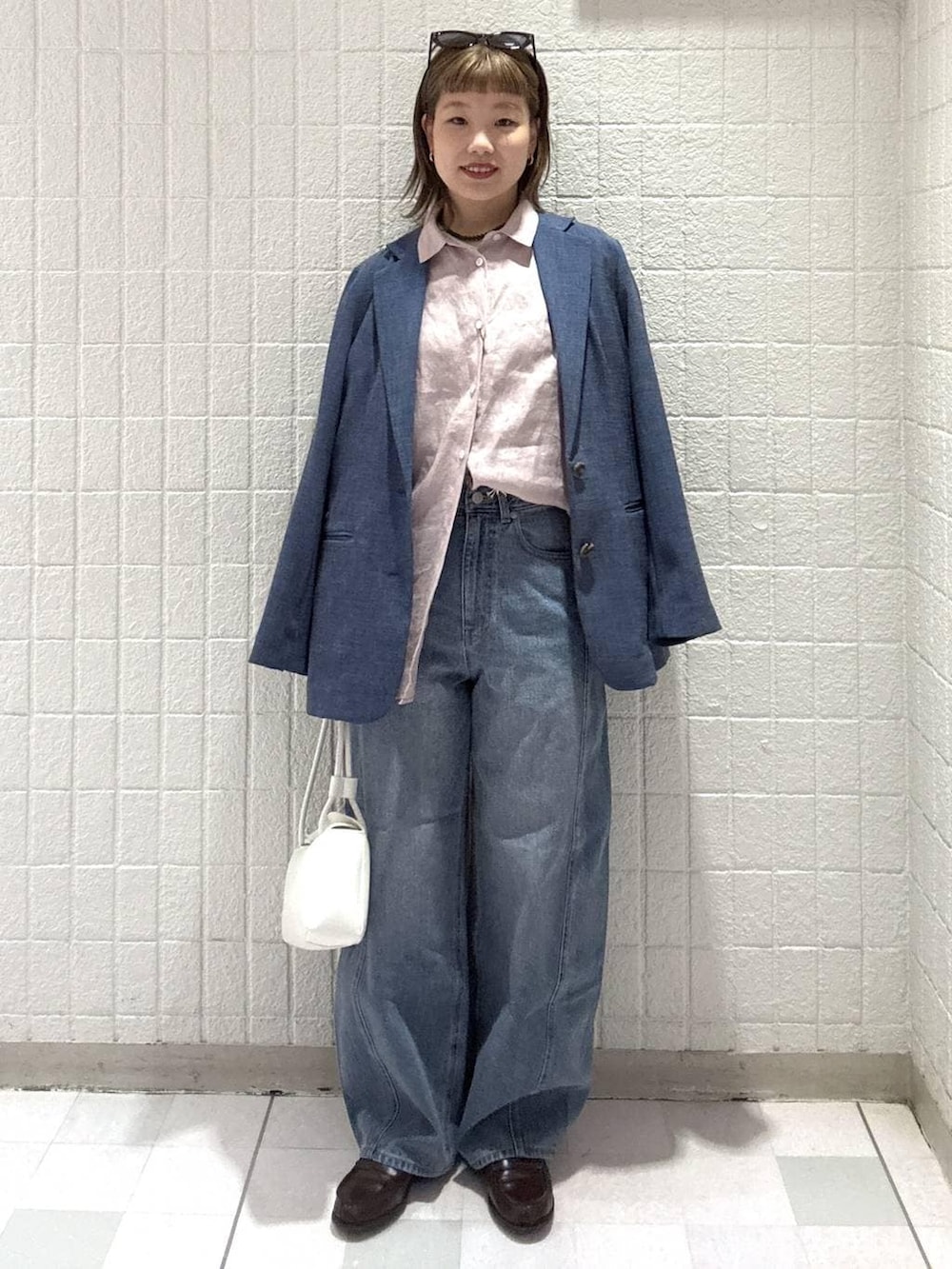 ブルー系のデニムパンツ、ピンク系のシャツ/ブラウス、ホワイト系のショルダーバッグを着用したレディースの春コーディネートの5枚目の写真