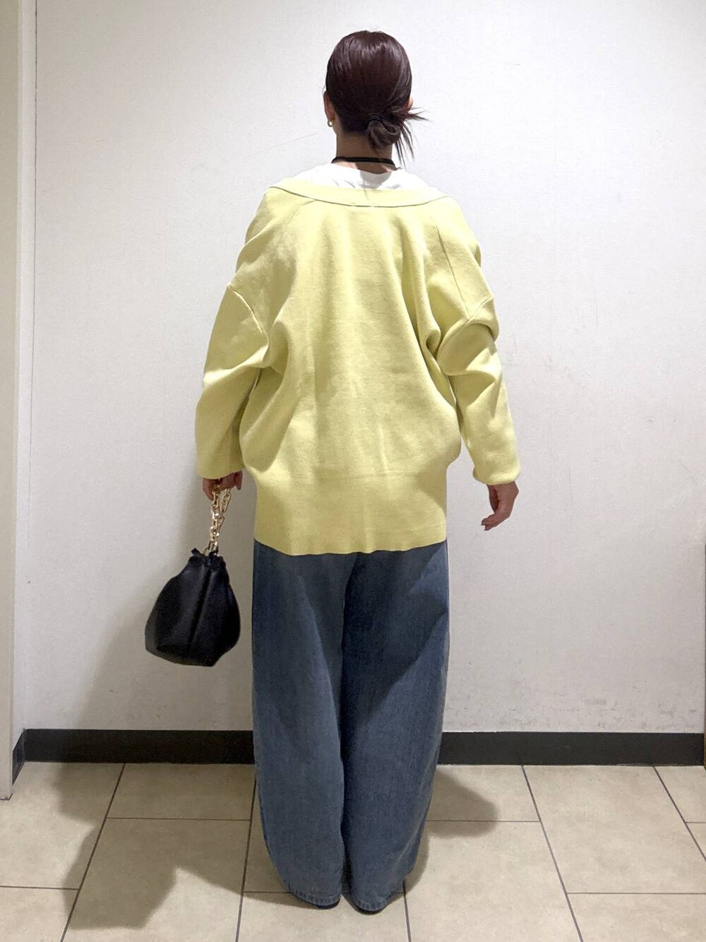 ブルー系のデニムパンツ、ブラック系のブーツ、イエロー系のカーディガン/ボレロを着用したレディースの冬コーディネートの4枚目の写真