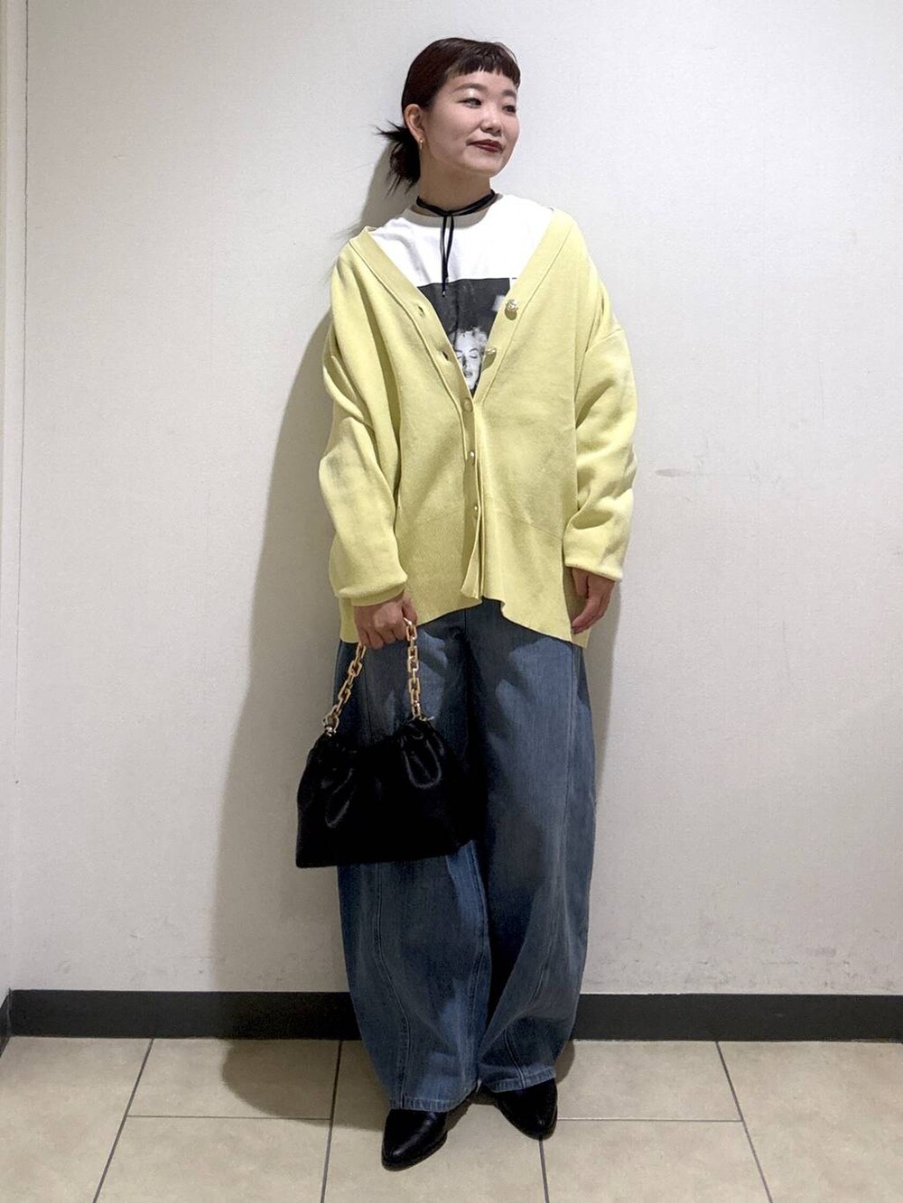 ブルー系のデニムパンツ、ブラック系のブーツ、イエロー系のカーディガン/ボレロを着用したレディースの冬コーディネートの2枚目の写真