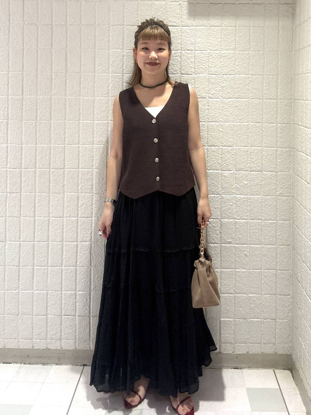 ベージュ系のショルダーバッグ、ブラウン系のベスト、レッド系のサンダルを着用したレディースの春コーディネートの2枚目の写真