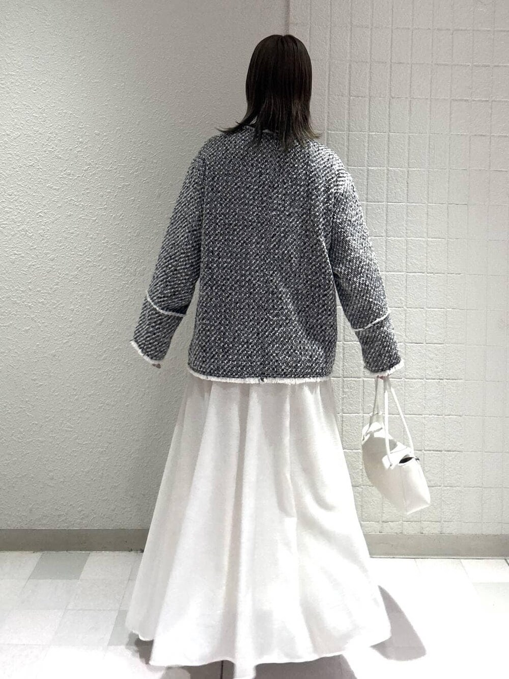 ホワイト系のスカート、ブラック系のノーカラージャケット、ホワイト系のショルダーバッグを着用したレディースの春コーディネートの4枚目の写真