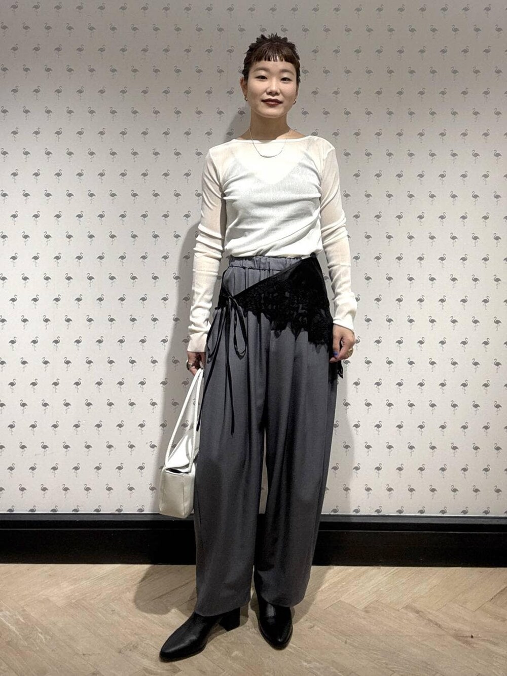 グレー系のスラックス、ホワイト系のTシャツ/カットソー、ブラック系のブーツを着用したレディースの冬コーディネートの5枚目の写真