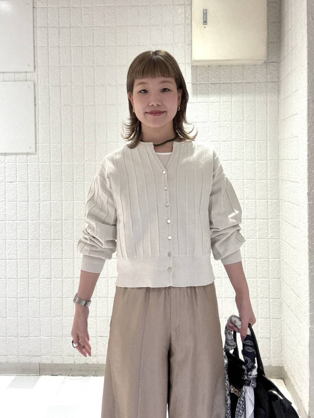 ホワイト系のカーディガン/ボレロ、ベージュ系のその他パンツ、ブラック系のショルダーバッグを着用したレディースの春コーディネートの6枚目の写真