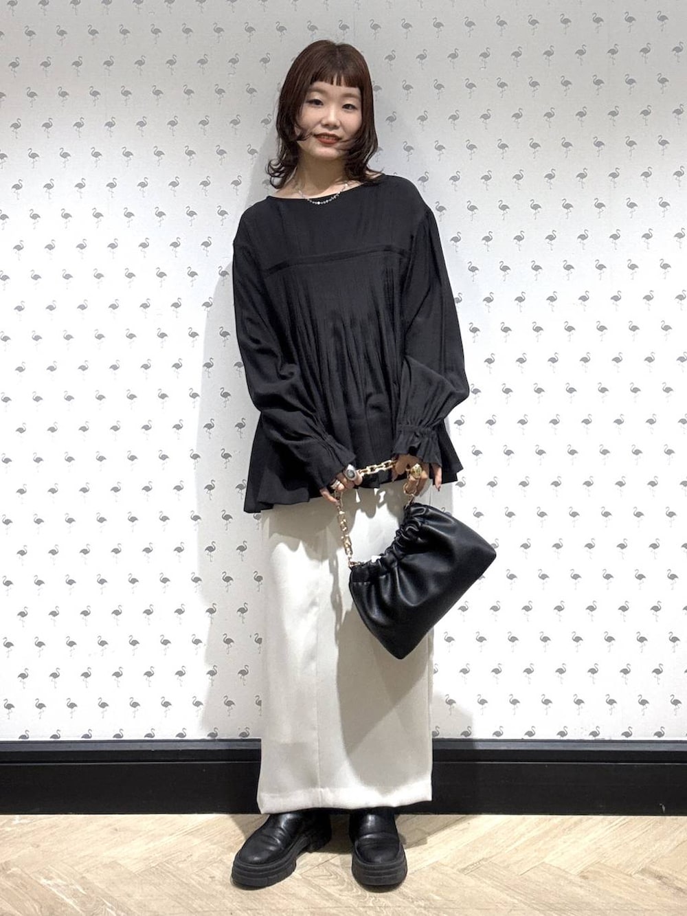 ブラック系のショルダーバッグ、ブラック系のシャツ/ブラウス、ホワイト系のスカートを着用したレディースの冬コーディネートの2枚目の写真