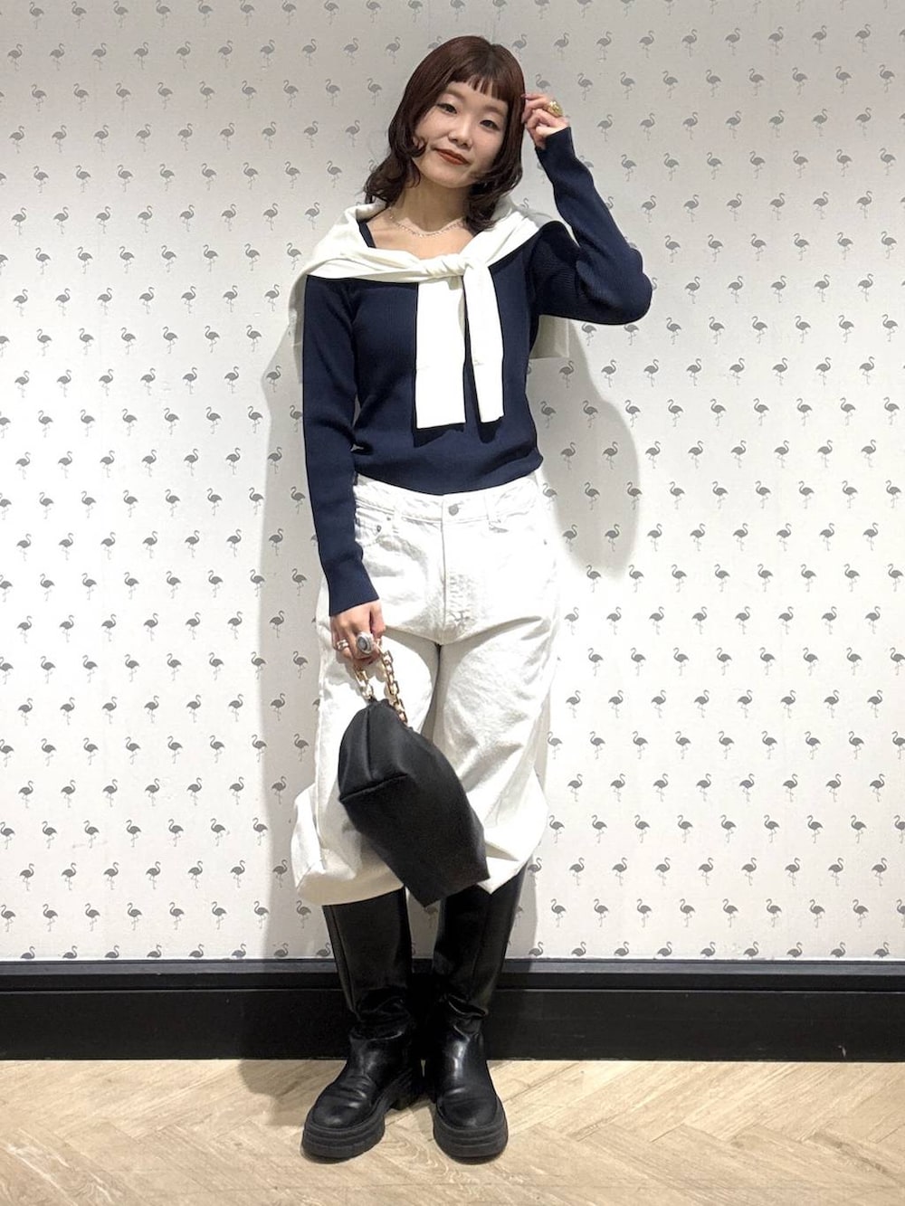 ブラック系のショルダーバッグ、ホワイト系のデニムパンツ、ホワイト系のカーディガン/ボレロを着用したレディースの冬コーディネートの2枚目の写真