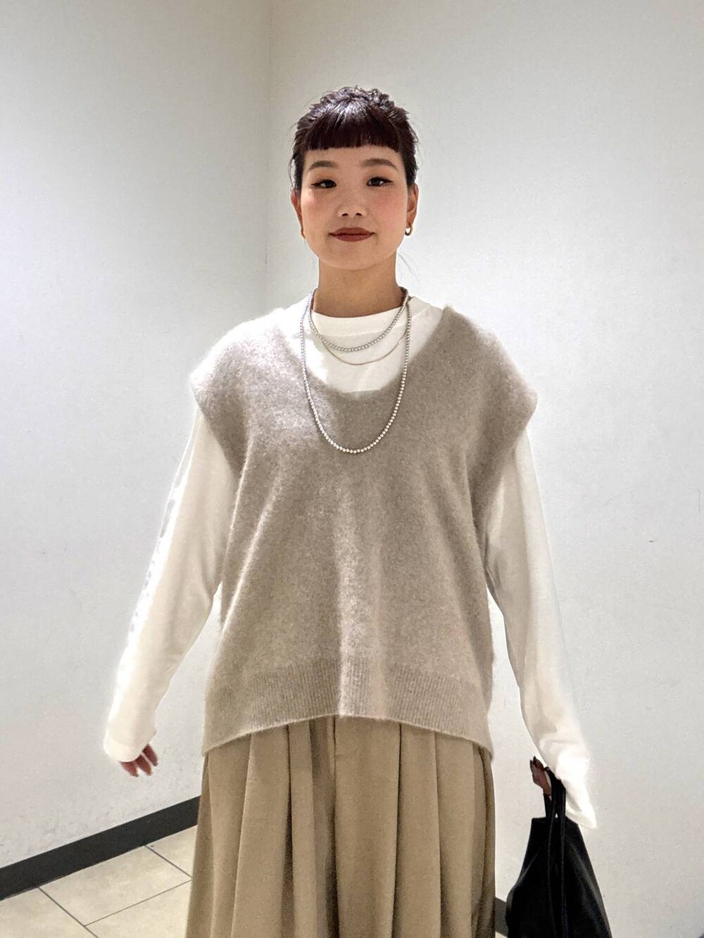 ベージュ系のスラックス、ブラック系のブーツ、ホワイト系のTシャツ/カットソーを着用したレディースの秋コーディネートの6枚目の写真