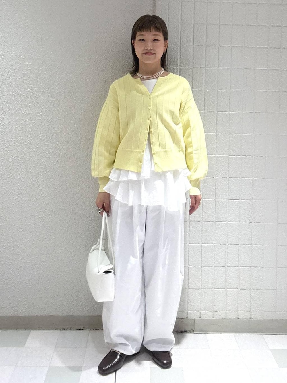 イエロー系のカーディガン/ボレロ、ホワイト系のシャツ/ブラウス、ホワイト系のショルダーバッグを着用したレディースの春コーディネートの4枚目の写真