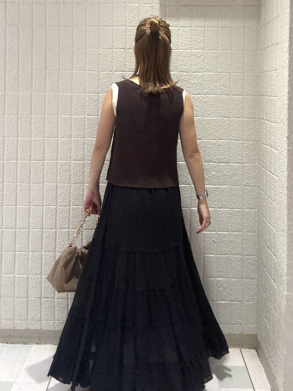 ベージュ系のショルダーバッグ、ブラウン系のベスト、レッド系のサンダルを着用したレディースの春コーディネートの4枚目の写真