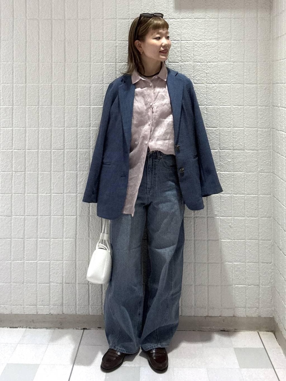 ブルー系のデニムパンツ、ピンク系のシャツ/ブラウス、ホワイト系のショルダーバッグを着用したレディースの春コーディネートの2枚目の写真