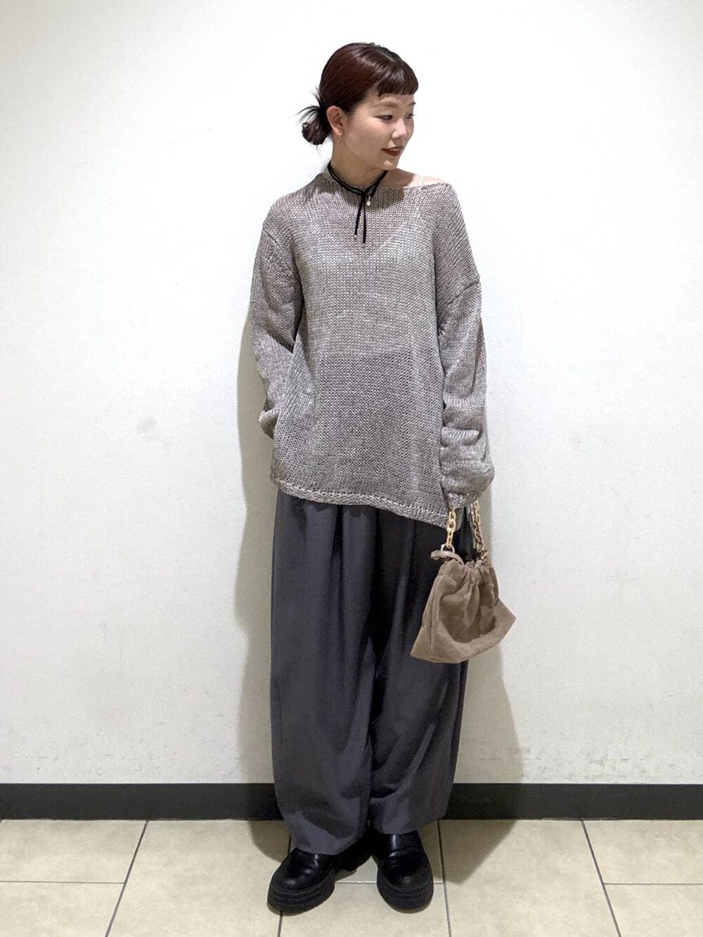 グレー系のスラックス、ベージュ系のショルダーバッグ、ホワイト系のキャミソールを着用したレディースの冬コーディネートの2枚目の写真