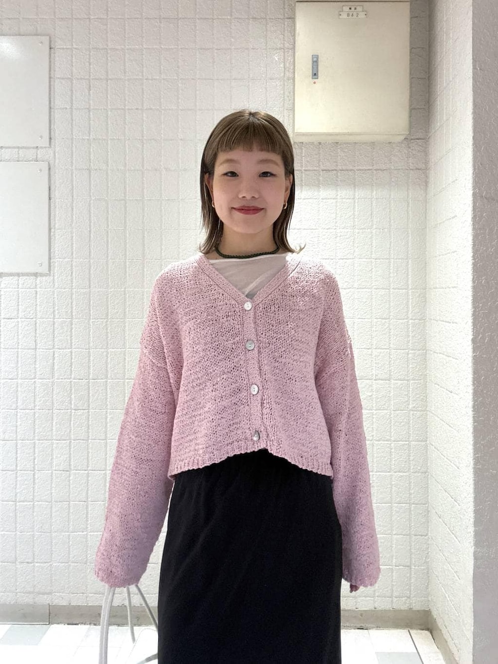 ホワイト系のショルダーバッグ、ピンク系のカーディガン/ボレロ、ブラック系のスカートを着用したレディースの春コーディネートの6枚目の写真