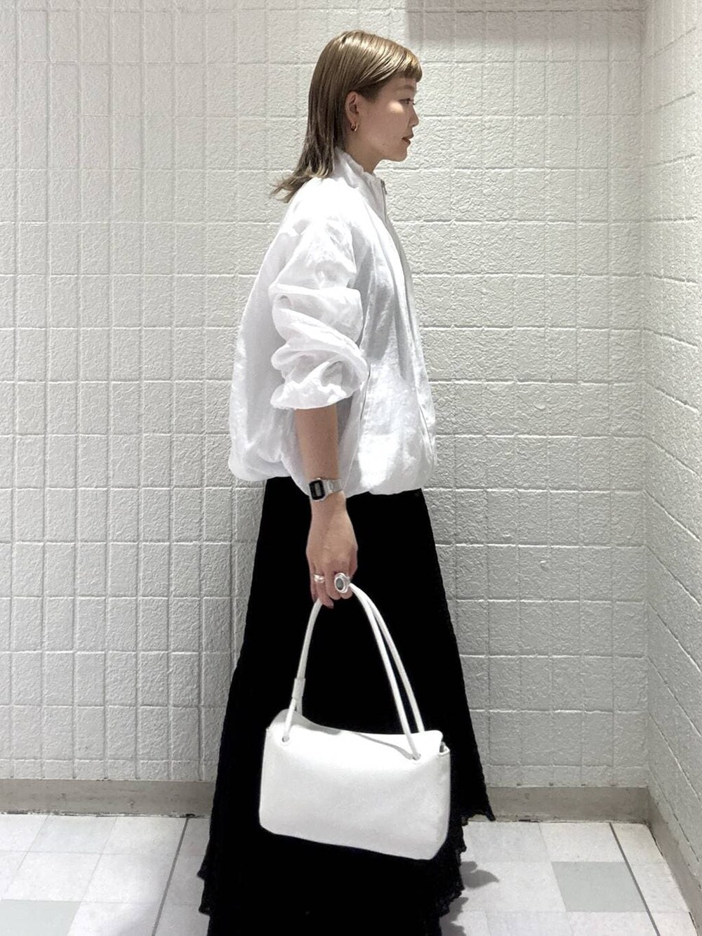 ホワイト系のショルダーバッグ、ホワイト系のブルゾン、ブラック系のワンピースを着用したレディースの春コーディネートの3枚目の写真