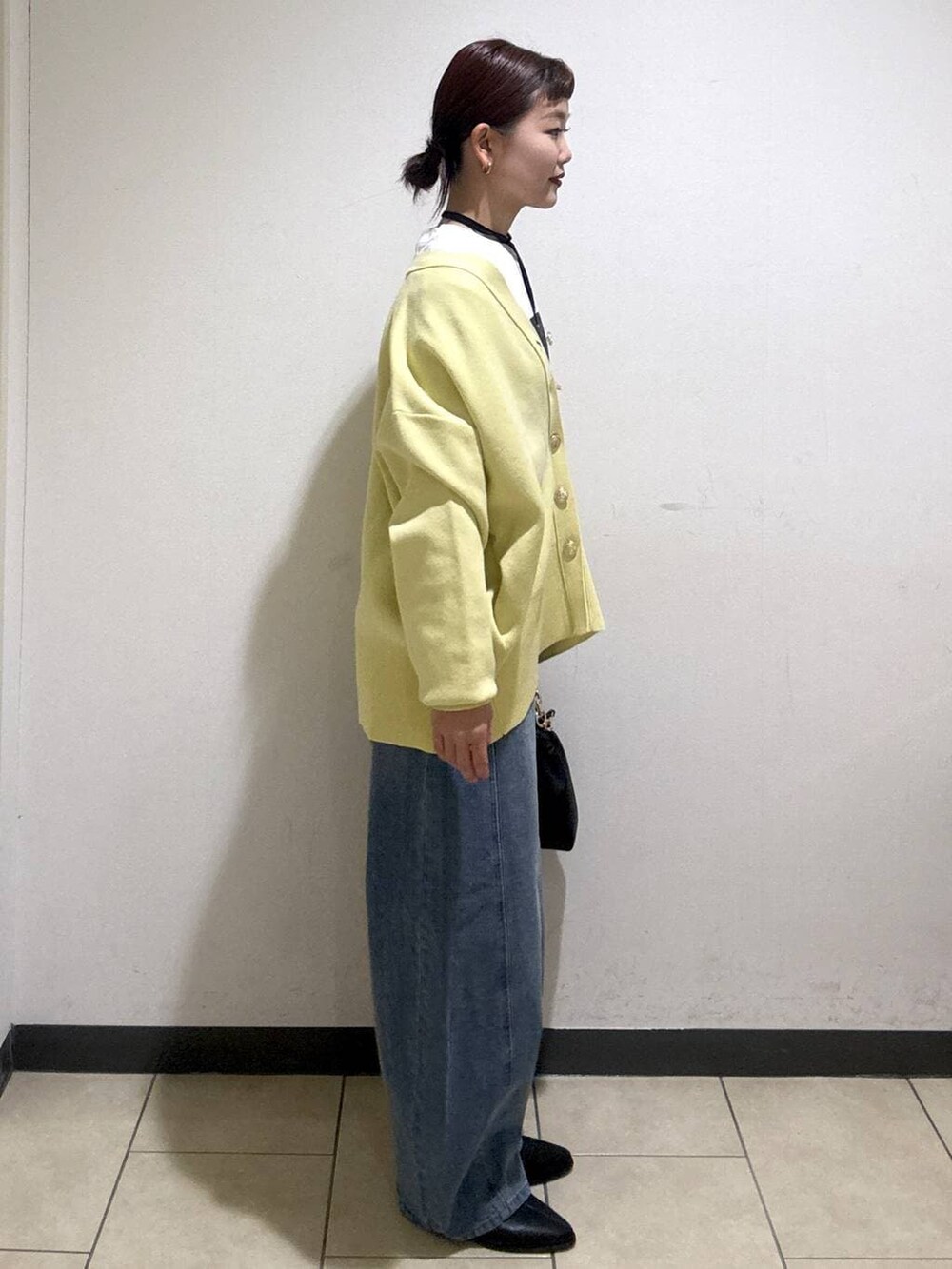 ブルー系のデニムパンツ、ブラック系のブーツ、イエロー系のカーディガン/ボレロを着用したレディースの冬コーディネートの3枚目の写真