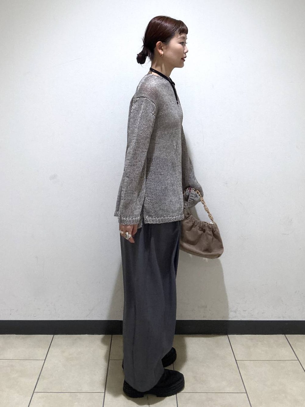 グレー系のスラックス、ベージュ系のショルダーバッグ、ホワイト系のキャミソールを着用したレディースの冬コーディネートの3枚目の写真