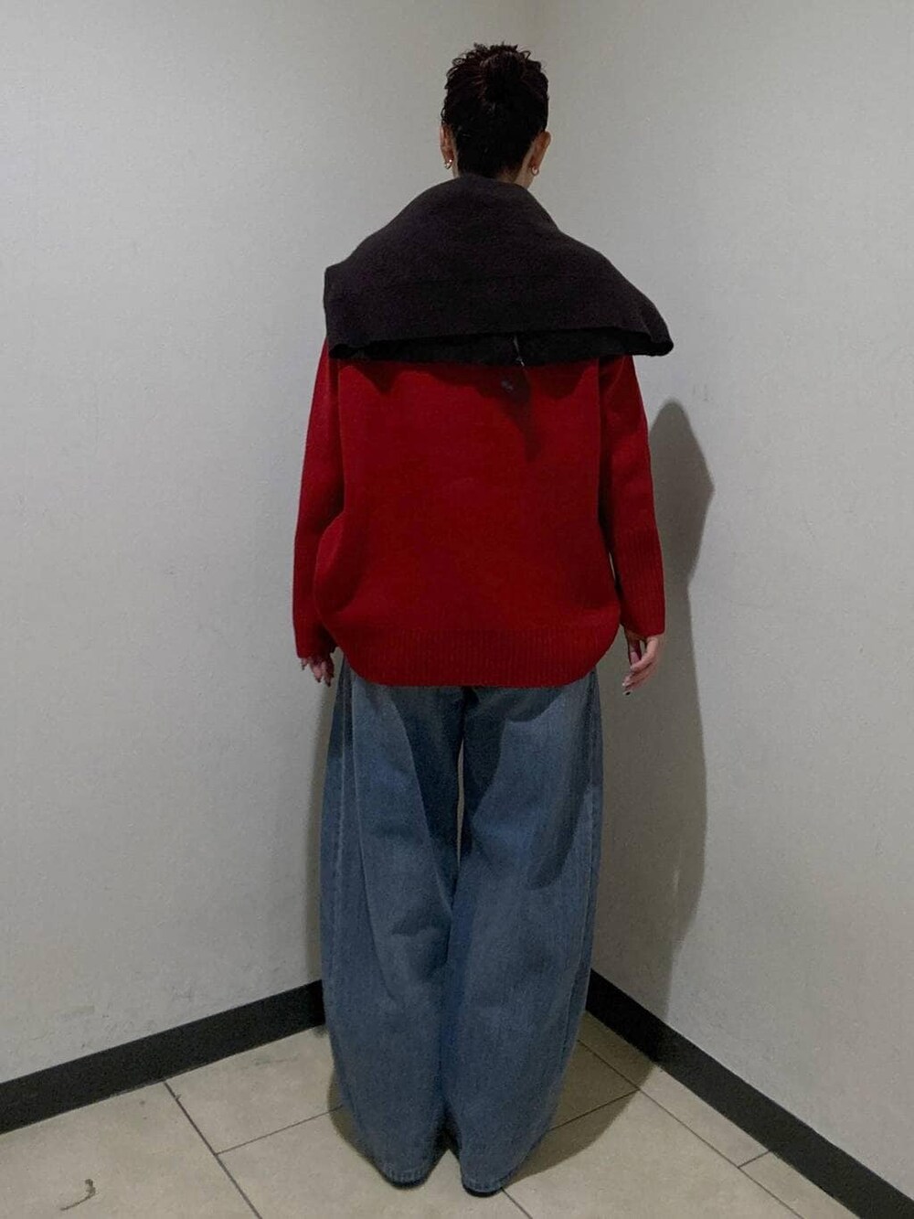 ブルー系のデニムパンツ、ブラック系のブーツ、レッド系のニット/セーターを着用したレディースの冬コーディネートの4枚目の写真