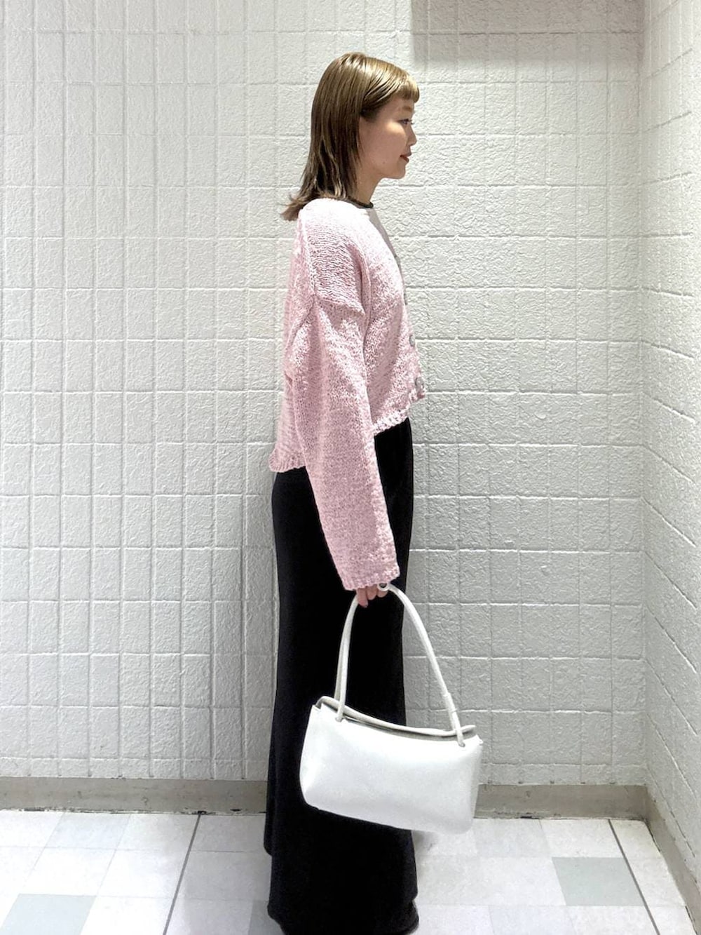 ホワイト系のショルダーバッグ、ピンク系のカーディガン/ボレロ、ブラック系のスカートを着用したレディースの春コーディネートの3枚目の写真