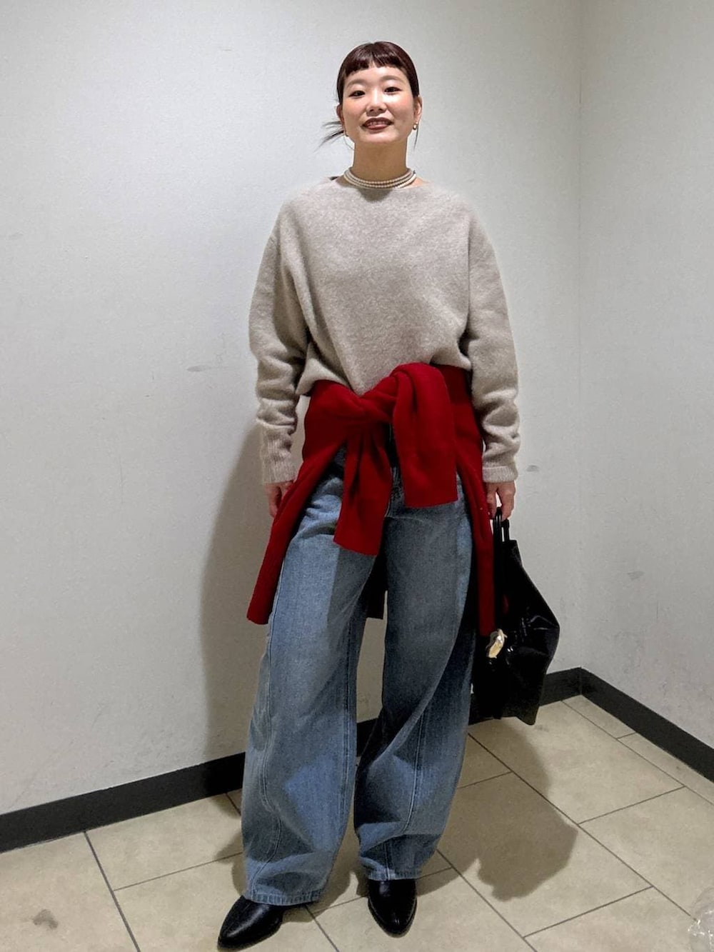 ベージュ系のニット/セーター、レッド系のカーディガン/ボレロ、ブルー系のデニムパンツを着用したレディースの冬コーディネートの5枚目の写真