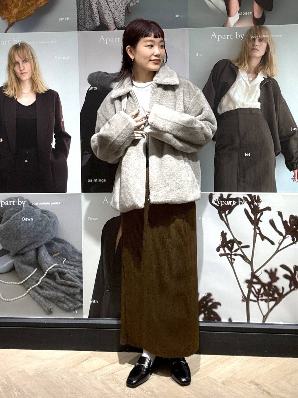 ブラック系のローファー、ブラウン系のスカート、ホワイト系のTシャツ/カットソーを着用したレディースの秋コーディネートの2枚目の写真