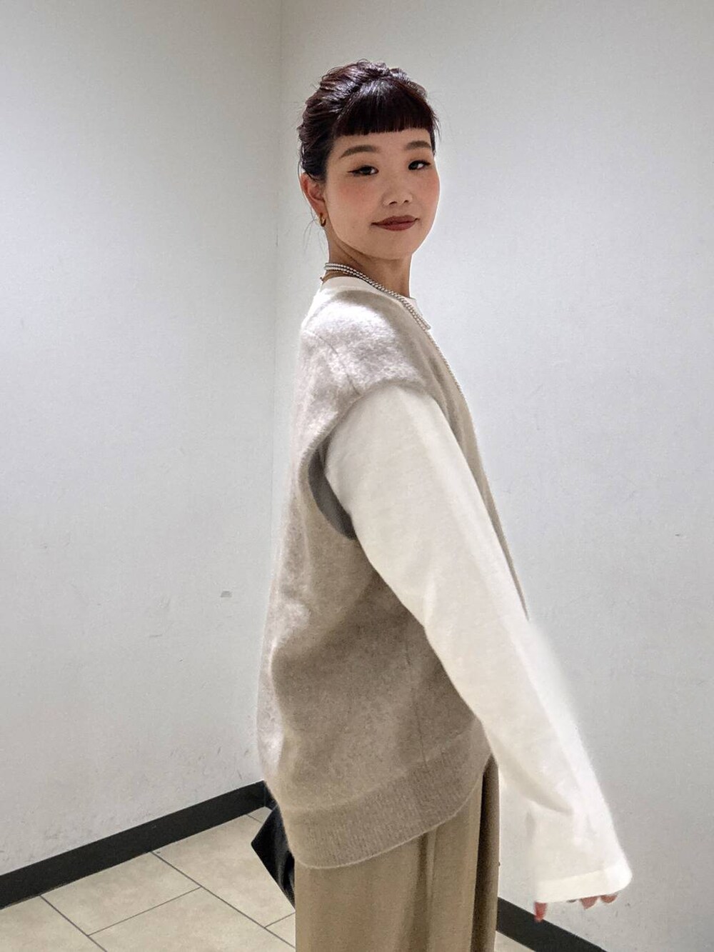 ベージュ系のスラックス、ブラック系のブーツ、ホワイト系のTシャツ/カットソーを着用したレディースの秋コーディネートの7枚目の写真