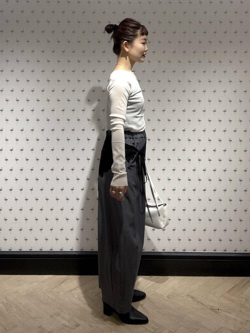 グレー系のスラックス、ホワイト系のTシャツ/カットソー、ブラック系のブーツを着用したレディースの冬コーディネートの3枚目の写真