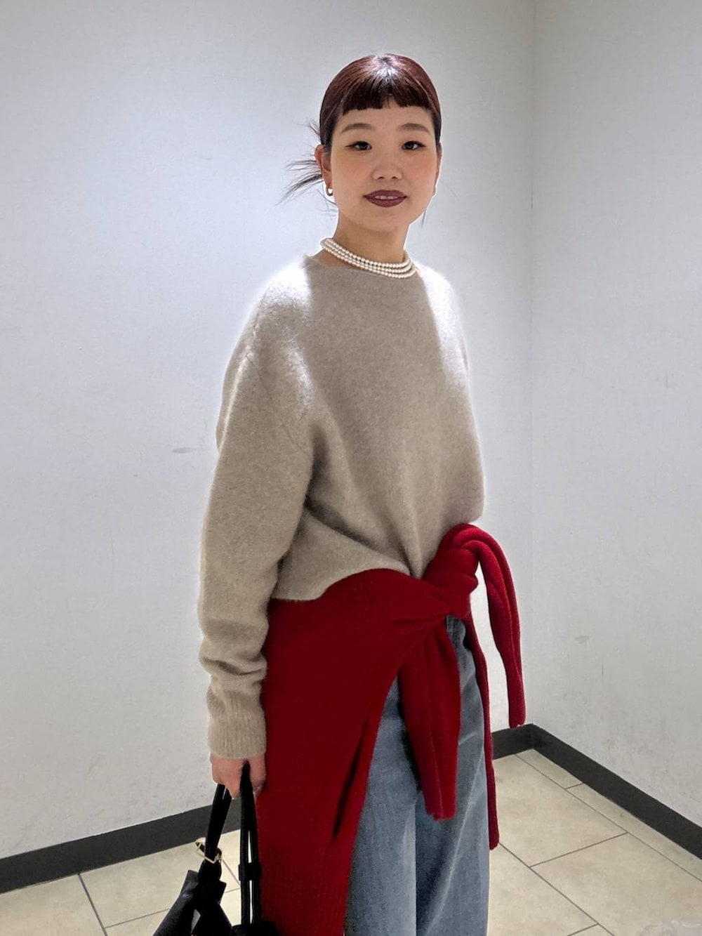 ベージュ系のニット/セーター、レッド系のカーディガン/ボレロ、ブルー系のデニムパンツを着用したレディースの冬コーディネートの7枚目の写真