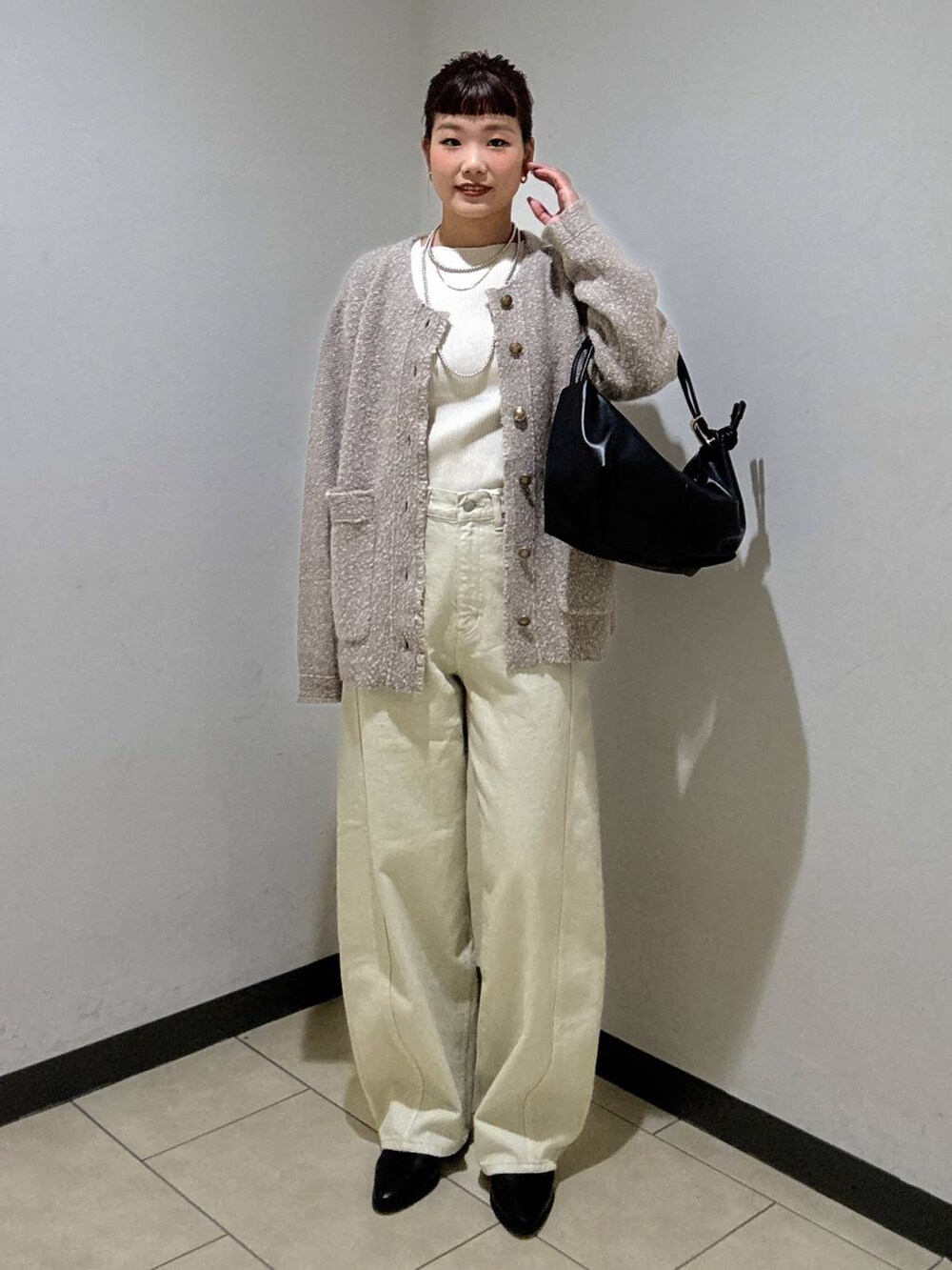 ベージュ系のデニムパンツ、ブラック系のブーツ、ホワイト系のニット/セーターを着用したレディースの秋コーディネートの2枚目の写真