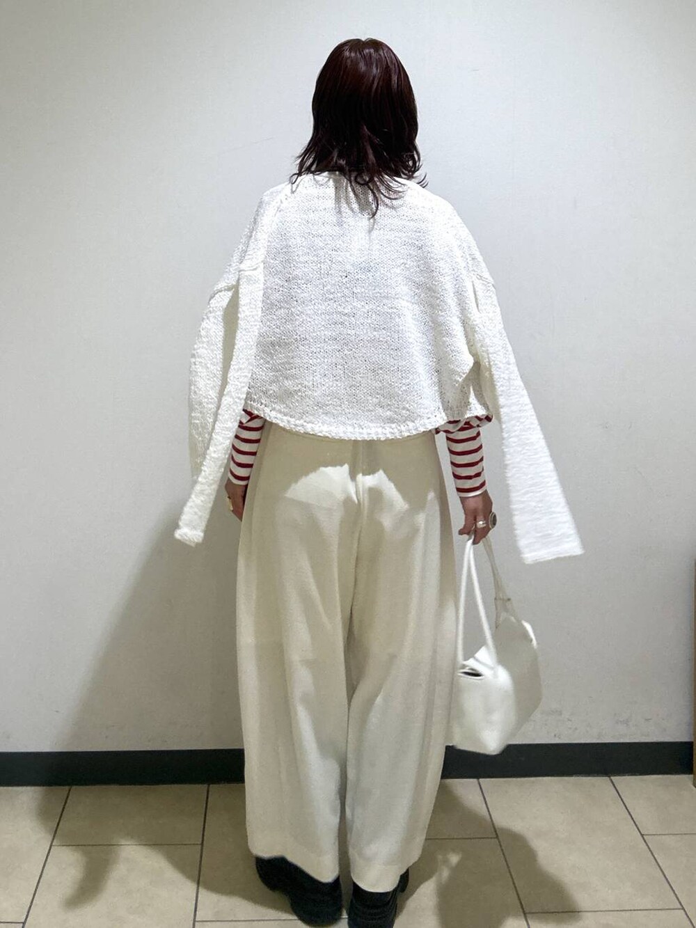 ホワイト系のスラックス、ブラック系のローファー、ホワイト系のショルダーバッグを着用したレディースの冬コーディネートの4枚目の写真