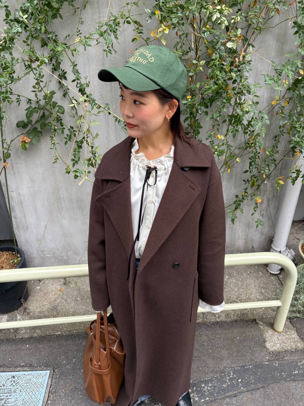 ブラウン系のステンカラーコート、ブルー系のデニムパンツ、ホワイト系のシャツ/ブラウスを着用したレディースの秋コーディネートの6枚目の写真