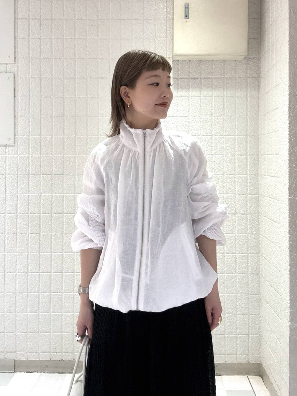 ホワイト系のショルダーバッグ、ホワイト系のブルゾン、ブラック系のワンピースを着用したレディースの春コーディネートの6枚目の写真