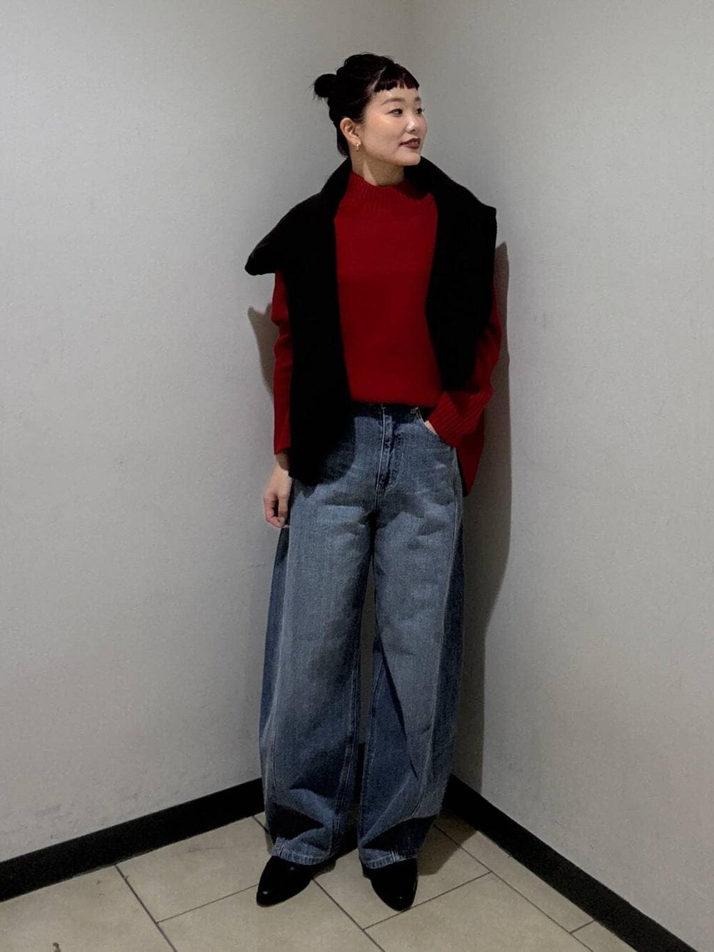 ブルー系のデニムパンツ、ブラック系のブーツ、レッド系のニット/セーターを着用したレディースの冬コーディネートの2枚目の写真