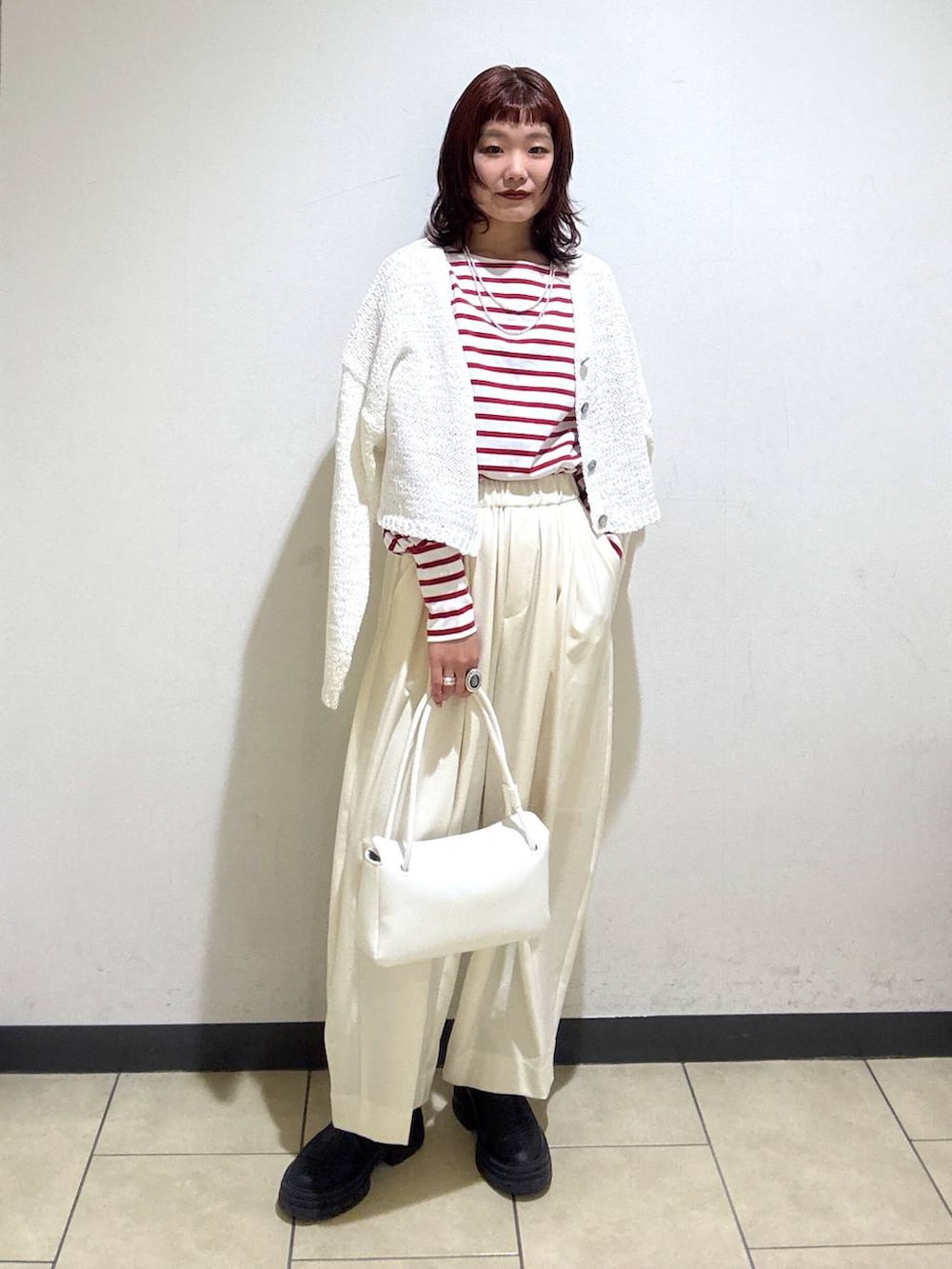 ホワイト系のスラックス、ブラック系のローファー、ホワイト系のショルダーバッグを着用したレディースの冬コーディネートの2枚目の写真