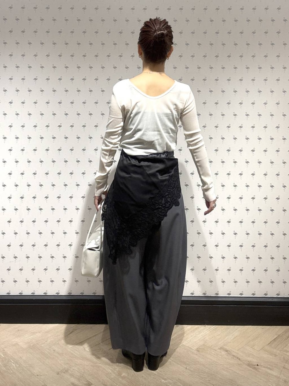 グレー系のスラックス、ホワイト系のTシャツ/カットソー、ブラック系のブーツを着用したレディースの冬コーディネートの4枚目の写真