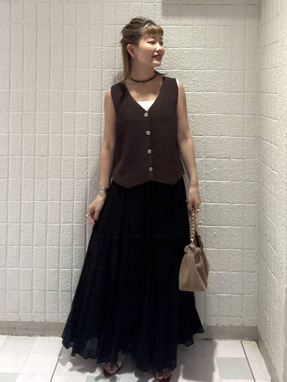 ベージュ系のショルダーバッグ、ブラウン系のベスト、レッド系のサンダルを着用したレディースの春コーディネートの5枚目の写真