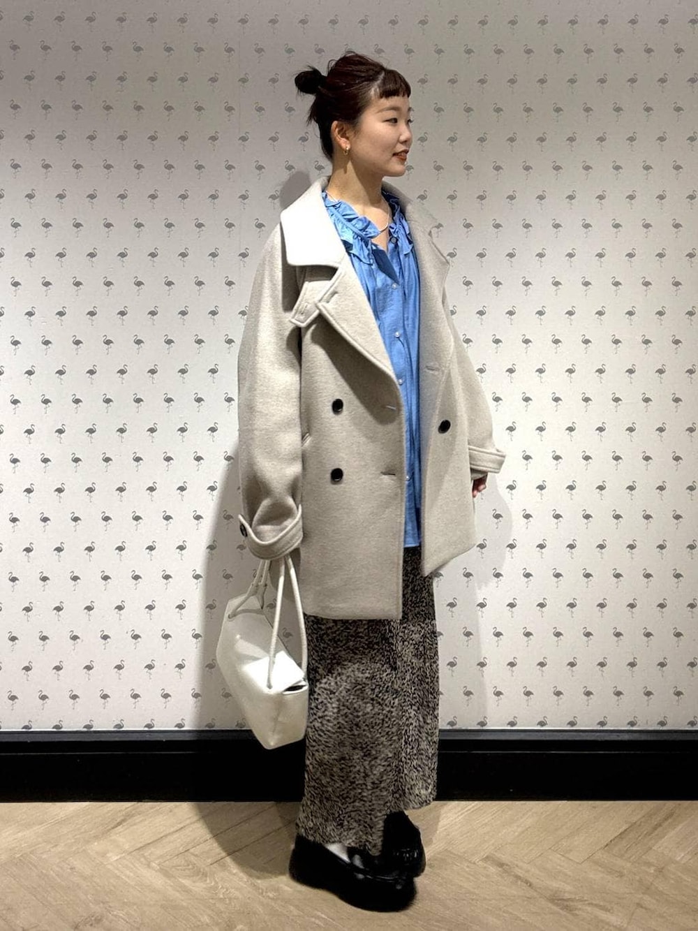 ベージュ系のピーコート、ブラウン系のスカート、ブラック系のローファーを着用したレディースの冬コーディネートの3枚目の写真