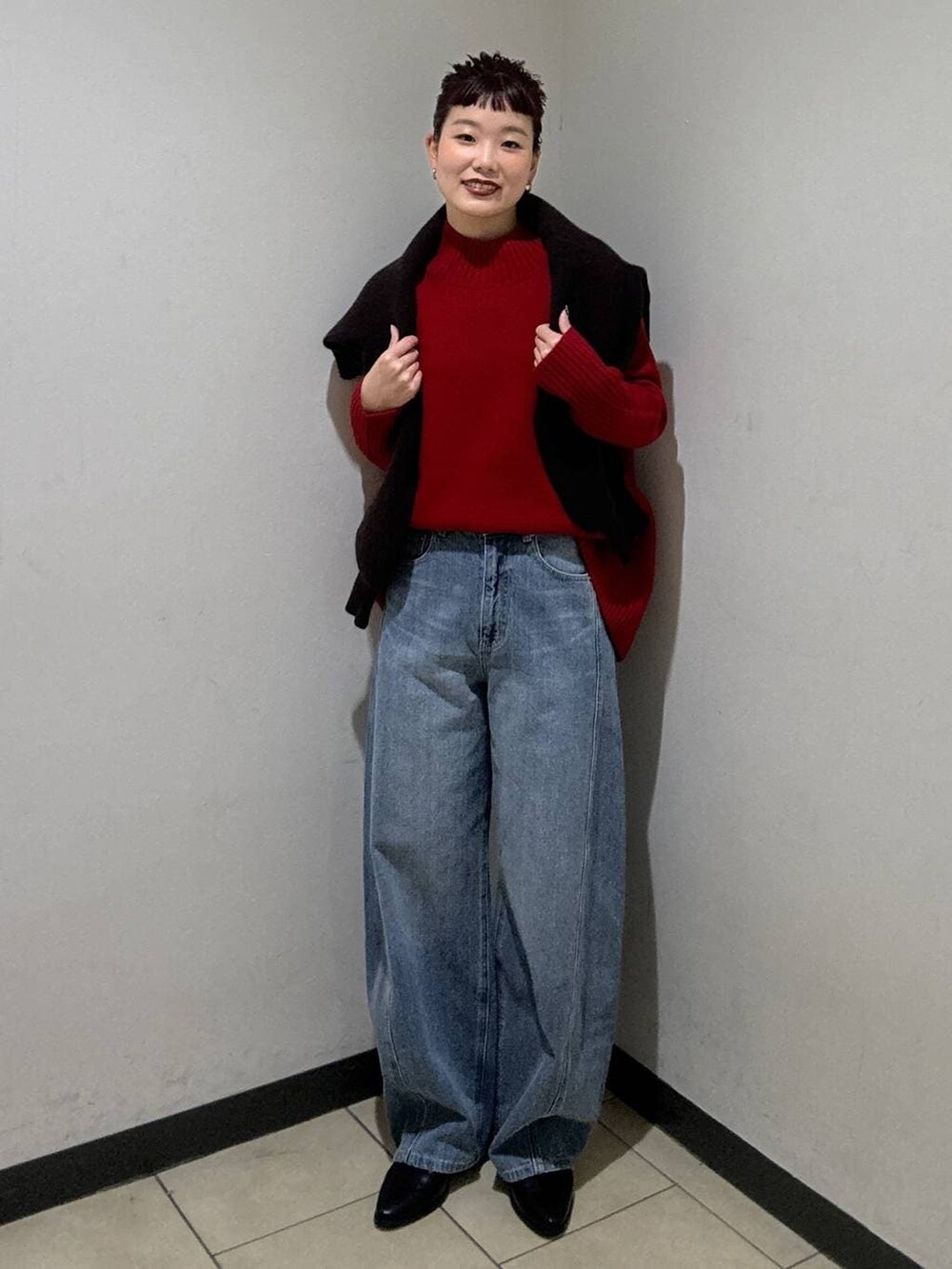 ブルー系のデニムパンツ、ブラック系のブーツ、レッド系のニット/セーターを着用したレディースの冬コーディネートの5枚目の写真