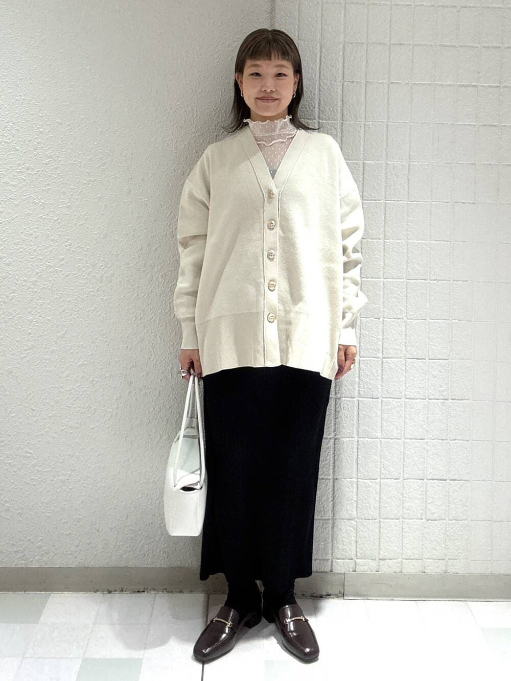 ホワイト系のカーディガン/ボレロ、ブラック系のスカート、ホワイト系のTシャツ/カットソーを着用したレディースの春コーディネートの5枚目の写真