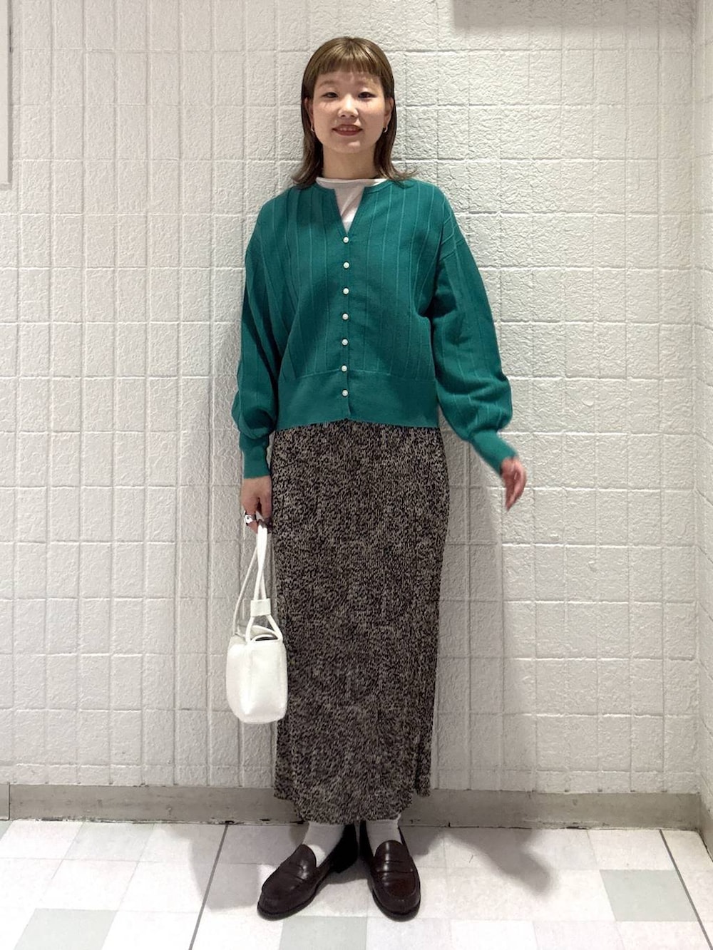 グリーン系のカーディガン/ボレロ、ブラウン系のスカート、ホワイト系のショルダーバッグを着用したレディースの春コーディネートの2枚目の写真