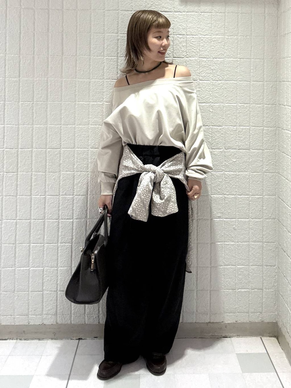 ブラック系のスラックス、ブラウン系のショルダーバッグ、ホワイト系のTシャツ/カットソーを着用したレディースの春コーディネートの2枚目の写真