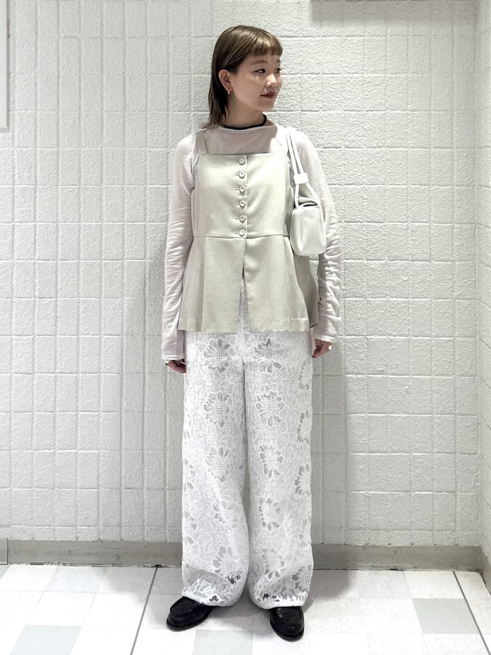 ベージュ系のベスト、ホワイト系のTシャツ/カットソー、ホワイト系のショルダーバッグを着用したレディースの春コーディネートの2枚目の写真