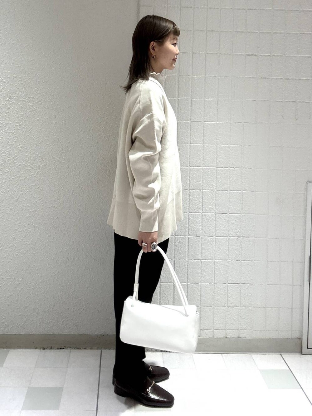 ホワイト系のカーディガン/ボレロ、ブラック系のスカート、ホワイト系のTシャツ/カットソーを着用したレディースの春コーディネートの3枚目の写真