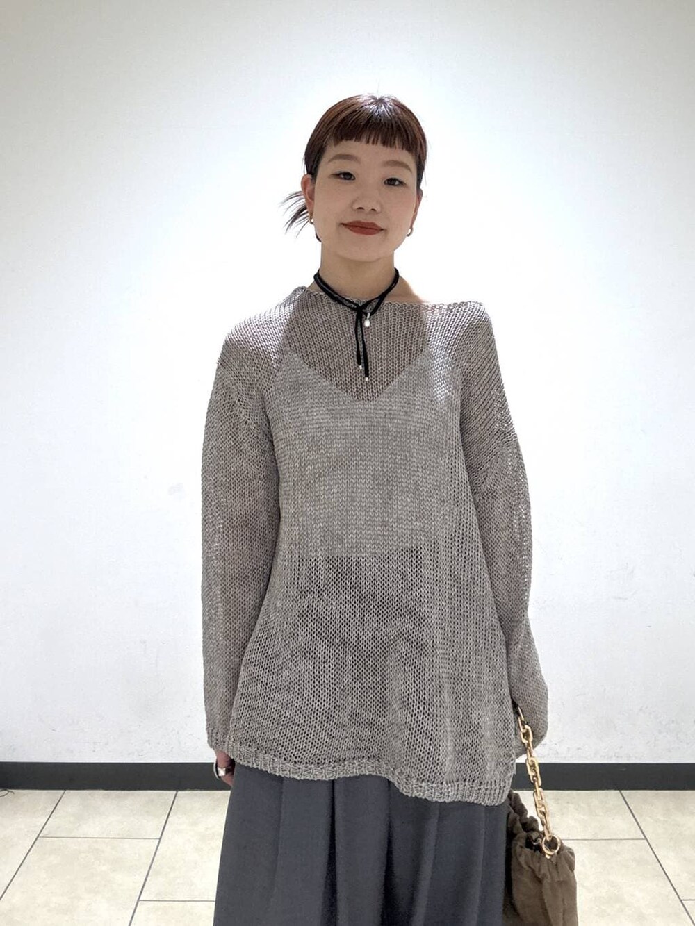 グレー系のスラックス、ベージュ系のショルダーバッグ、ホワイト系のキャミソールを着用したレディースの冬コーディネートの6枚目の写真