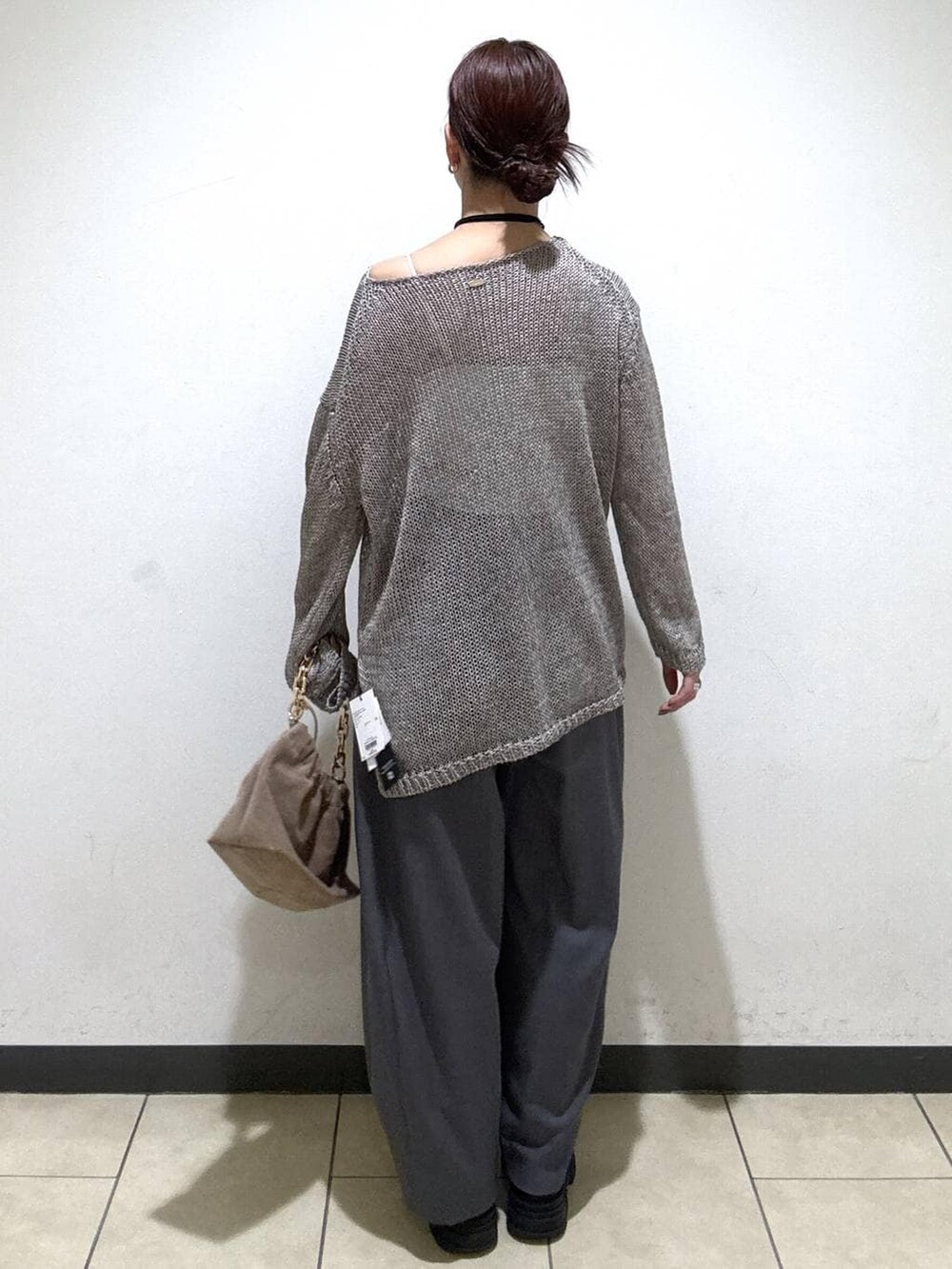 グレー系のスラックス、ベージュ系のショルダーバッグ、ホワイト系のキャミソールを着用したレディースの冬コーディネートの4枚目の写真