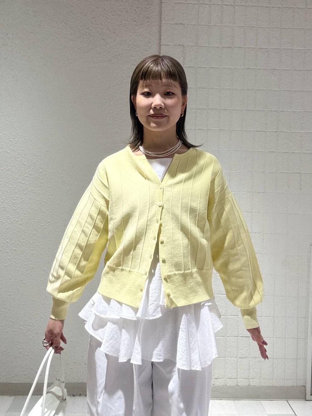 イエロー系のカーディガン/ボレロ、ホワイト系のシャツ/ブラウス、ホワイト系のショルダーバッグを着用したレディースの春コーディネートの5枚目の写真