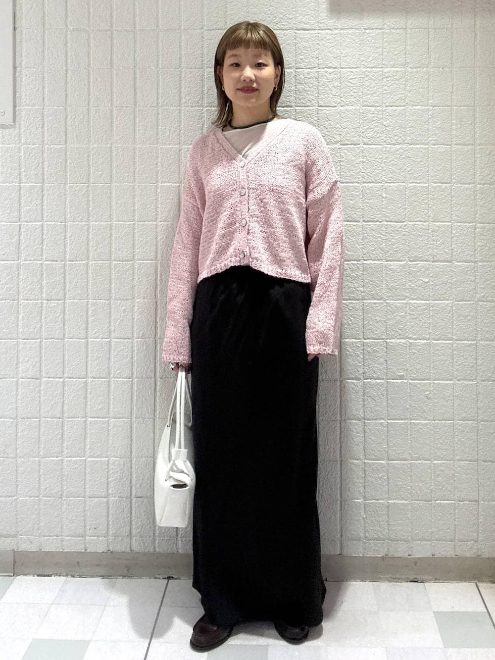 ホワイト系のショルダーバッグ、ピンク系のカーディガン/ボレロ、ブラック系のスカートを着用したレディースの春コーディネートの5枚目の写真