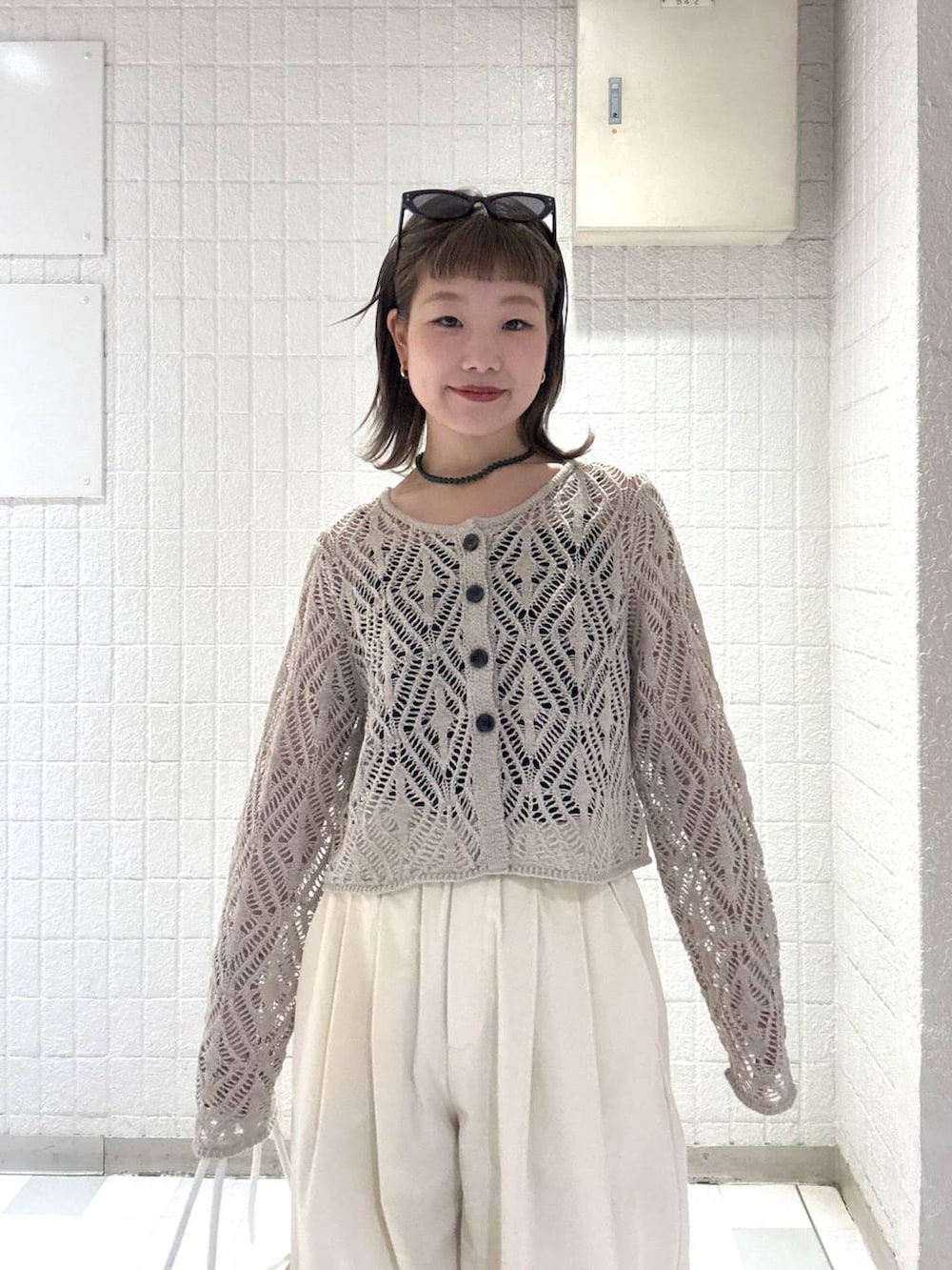 ホワイト系のショルダーバッグ、ベージュ系のカーディガン/ボレロ、ブラウン系のサングラスを着用したレディースの春コーディネートの6枚目の写真