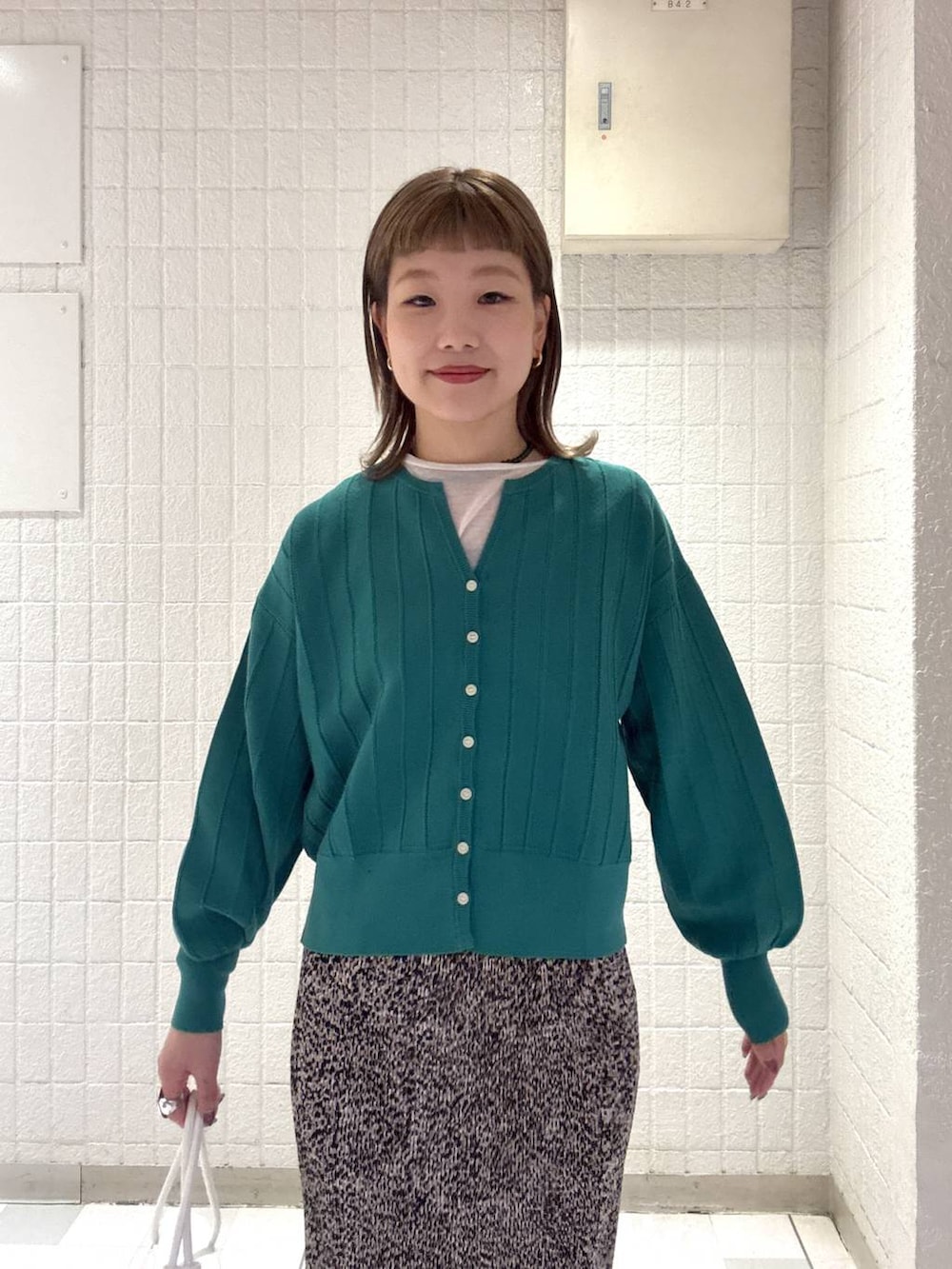 グリーン系のカーディガン/ボレロ、ブラウン系のスカート、ホワイト系のショルダーバッグを着用したレディースの春コーディネートの6枚目の写真