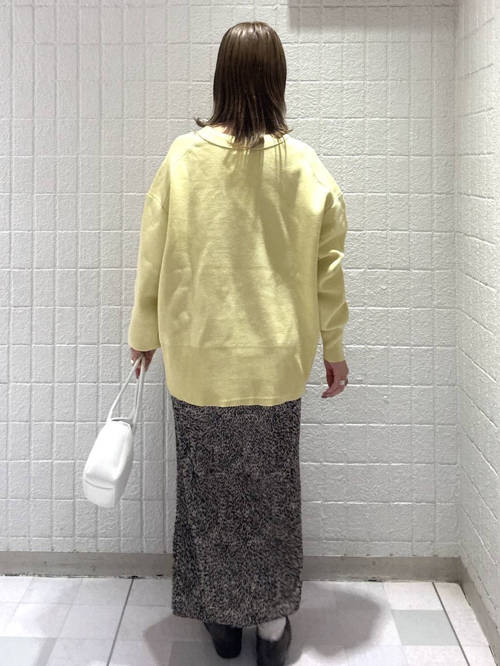 イエロー系のカーディガン/ボレロ、ブラウン系のスカート、ホワイト系のショルダーバッグを着用したレディースの春コーディネートの4枚目の写真